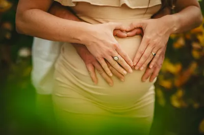 Couple's hands forming heart shape on baby bump, fertility and prenatal nutrition support